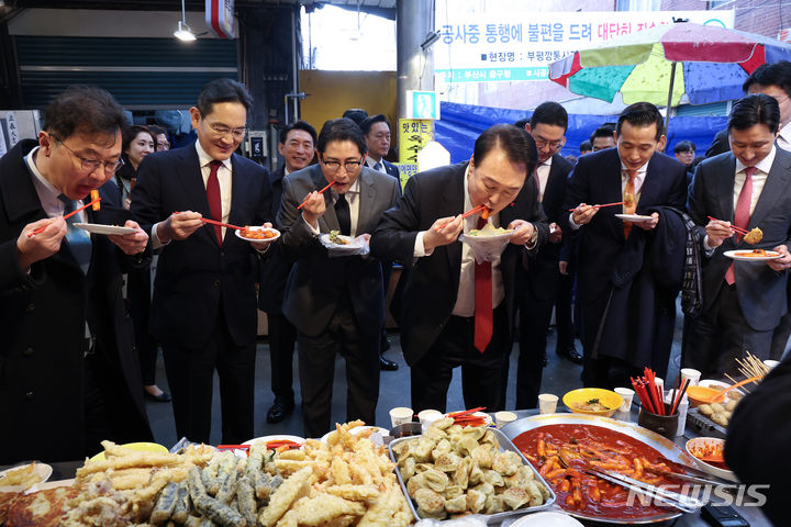 [부산=뉴시스] 전신 기자 = 윤석열 대통령이 6일 부산 중구 깡통시장을 방문해 기업인들과 떡볶이를 맛보고 있다. 왼쪽부터 최재원 SK 수석부회장, 이재용 삼성전자 회장, 조현준 효성 그룹 회장, 윤 대통령, 구광모 LG그룹 회장, 김동관 한화그룹 부회장, 정기선 HD현대 부회장. (대통령실통신사진기자단) 2023.12.06. photo1006@newsis.com