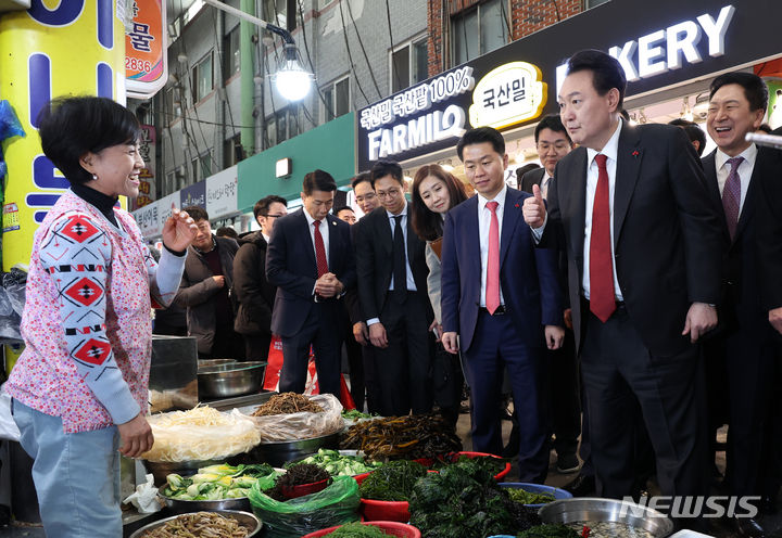 [부산=뉴시스] 전신 기자 = 윤석열 대통령이 6일 부산 중구 깡통시장을 방문해 상점의 민물새우를 맛본 뒤 상인에게 엄지를 들어보이고 있다. (대통령실통신사진기자단) 2023.12.06. photo1006@newsis.com