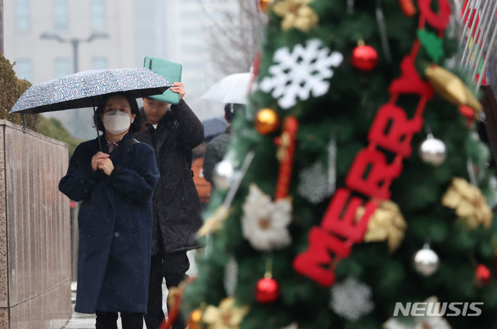[서울=뉴시스] 김명년 기자 = 겨울비가 내린 6일 오후 서울 중구 세종대로에서 한 시민이 노트로 비를 피하며 발걸음을 재촉하고 있다. 2023.12.06. kmn@newsis.com