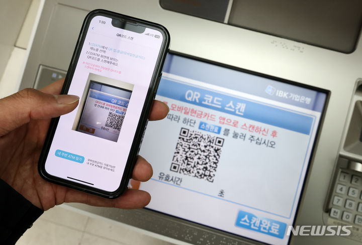 [서울=뉴시스] 조성우 기자 = 금융정보화추진협의회는 금융결제원 및 17개 국내은행과 함께 스마트폰 기종의 제한 없이 모바일현금카드 앱 및 모바일뱅킹 앱을 이용해 은행권 현금자동입출금기(ATM) 입출금을 가능하도록 하는 'QR코드 방식의 ATM 입출금 서비스'를 개시한다고 밝혔다. 사진은 6일 서울 시내의 한 ATM 기기와 모바일현금카드 앱 화면 모습. 2023.12.06. xconfind@newsis.com