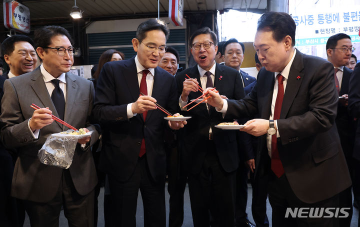 [부산=뉴시스] 전신 기자 = 윤석열 대통령이 6일 부산 중구 깡통시장을 방문해 이재용(왼쪽 세번째) 삼성전자 회장, 조현준(왼쪽 두번째) 효성그룹 회장 등에게 빈대떡을 나눠주고 있다. (대통령실통신사진기자단) 2023.12.06. photo1006@newsis.com