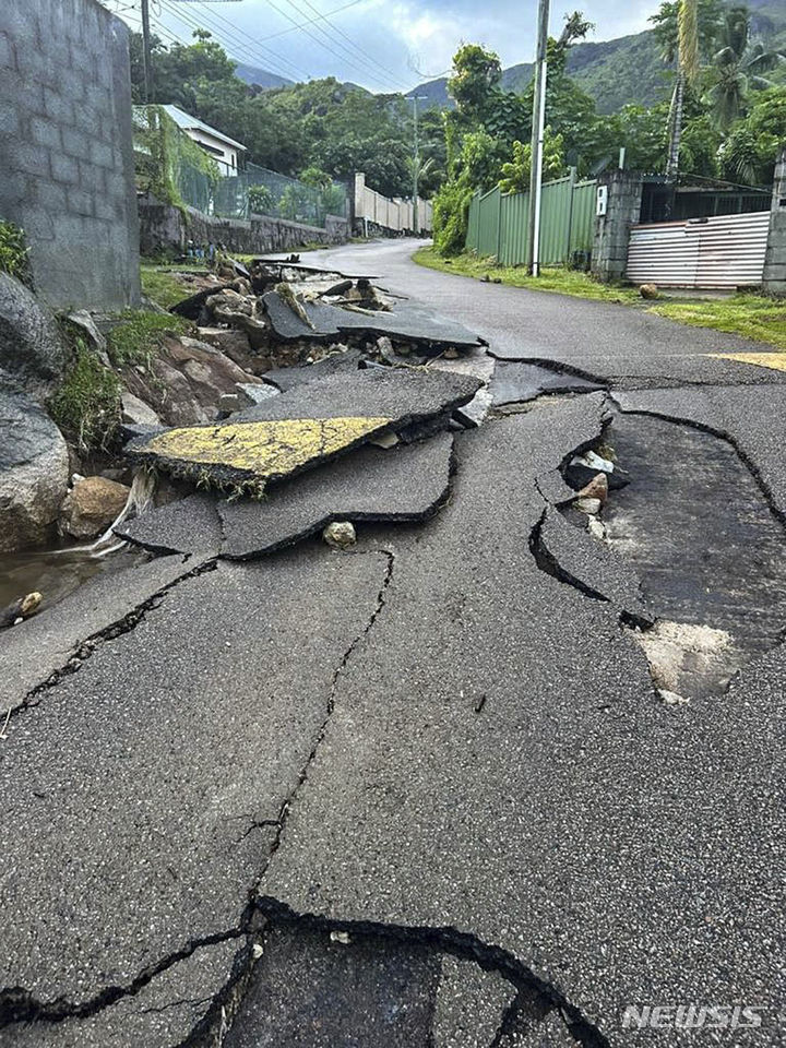 [마헤섬(세이셸)=AP/뉴시스]동아프리카 세이셸의 최대 섬 마헤섬 프로비던스 지역의 도로가 7일 새벽 간밤에 일어난 폭발물 보관소의 폭발로 갈라져 있다. 세이셸이 7일 폭우로 홍수가 발생한 산업 지역의 폭발물 보관소에서 일어난 폭발로 막대한 피해가 발생함에 따라 이 지역에 비상사태를 선포했다. 2023.12.07.