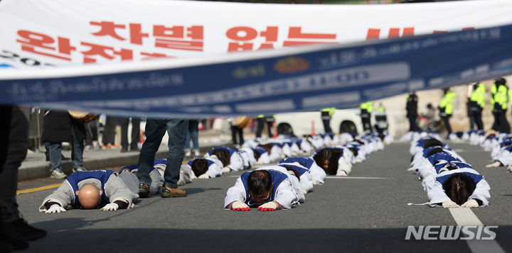 [서울=뉴시스] 김진아 기자 = 서울장애인부모연대 관계자들이 7일 서울 종로구 정부서울청사 앞에서 열린 전국 오체투지 보고대회 및 서울 오체투지 선포식을 마친 후 서울시청으로 오체투지 행진을 하고 있다. 전국장애인부모연대는 '차별없는 세상, 완전한 통합사회 구축'이라는 슬로건 아래, 발달장애인이 자립 생활할 권리, 통합교육을 받을 권리, 노동할 권리 등을 촉구하며 제주에서 서울까지 전국 각지에서 오체투지 행진을 진행했다. 2023.12.07. bluesoda@newsis.com