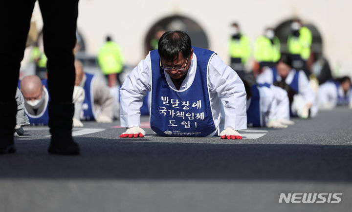 [서울=뉴시스] 김진아 기자 = 서울장애인부모연대 관계자들이 7일 서울 종로구 정부서울청사 앞에서 열린 전국 오체투지 보고대회 및 서울 오체투지 선포식을 마친 후 서울시청으로 오체투지 행진을 하고 있다. 전국장애인부모연대는 '차별없는 세상, 완전한 통합사회 구축'이라는 슬로건 아래, 발달장애인이 자립 생활할 권리, 통합교육을 받을 권리, 노동할 권리 등을 촉구하며 제주에서 서울까지 전국 각지에서 오체투지 행진을 진행했다. 2023.12.07. bluesoda@newsis.com