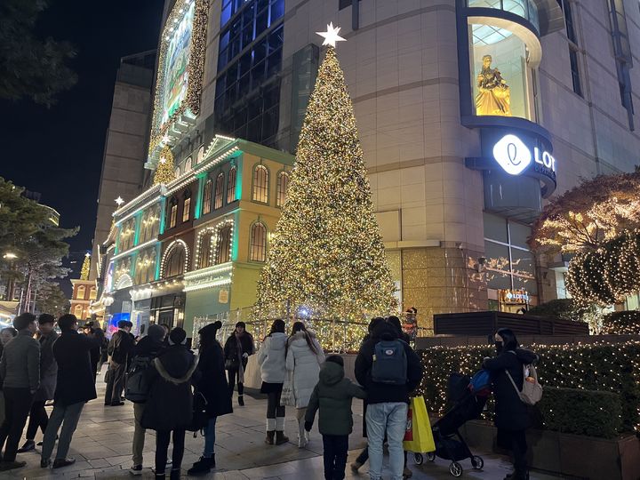 롯데백화점 본점 앞의 대형 트리를 배경으로 사람들이 사진을 찍고 있다. *재판매 및 DB 금지