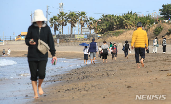 [제주=뉴시스] 우장호 기자 = 지난달 10일 오후 제주시 이호해수욕장을 찾은 시민들이 맨발로 해변을 걸어가고 있는 모습. 2023.12.10. woo1223@newsis.com