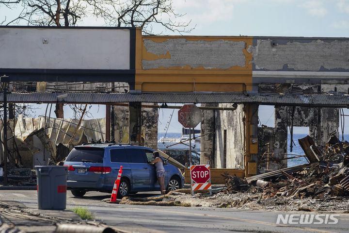 [하와이=AP/뉴시스] 미국 역사상 100년 만에 가장 큰 피해를 낸 하와이 산불이 발생한 지 약 넉 달 만에 마우이섬 라하이나 중심부가 일부 주민과 사업자들에게 재개방됐다고 미국 AP통신이 11일(현지시간) 전했다. 사진은 미국 하와이 라하이나 프론트스트리트에서 화재로 전소된 건물 앞에서 이야기 중인 사람들의 모습. 2023.12.12.