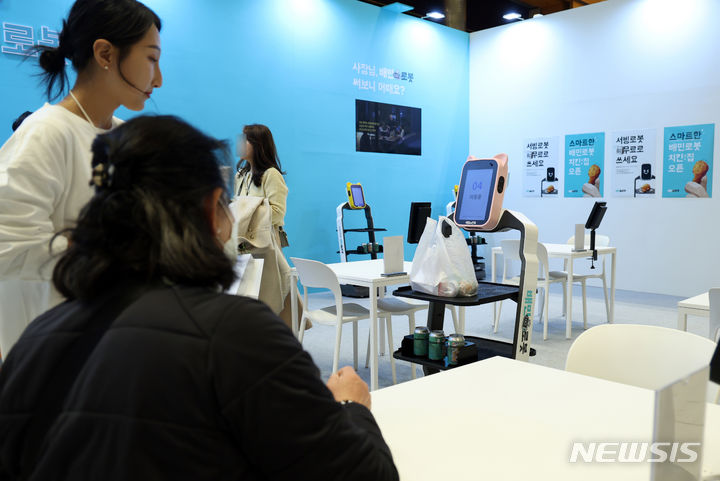 [서울=뉴시스] 고승민 기자 = 12일 서울 코엑스에서 열린 '배민 사장님 페스타'를 찾은 자영업자와 예비창업자들이 음식 서빙 로봇을 체험하고 있다. 2023.12.12. kkssmm99@newsis.com