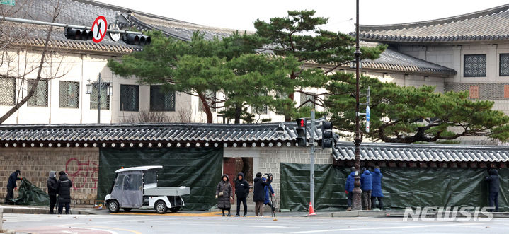 [서울=뉴시스] 김금보 기자 = 문화재청 궁능유적본부 직원들이 16일 오전 서울 종로구 국립고궁박물관 방향 경복궁 서편에서 스프레이 낙서로 훼손된 담벼락을 천으로 덮고 있다. 2023.12.16. kgb@newsis.com