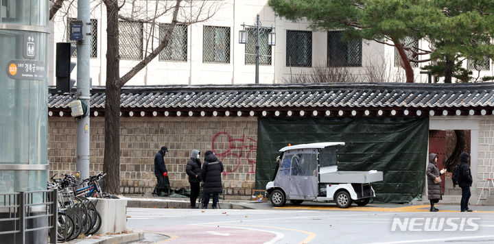 [서울=뉴시스] 김금보 기자 = 문화재청 궁능유적본부 직원들이 16일 오전 서울 종로구 국립고궁박물관 방향 경복궁 서편에서 스프레이 낙서로 훼손된 담벼락을 천으로 덮고 있다. 2023.12.16. kgb@newsis.com