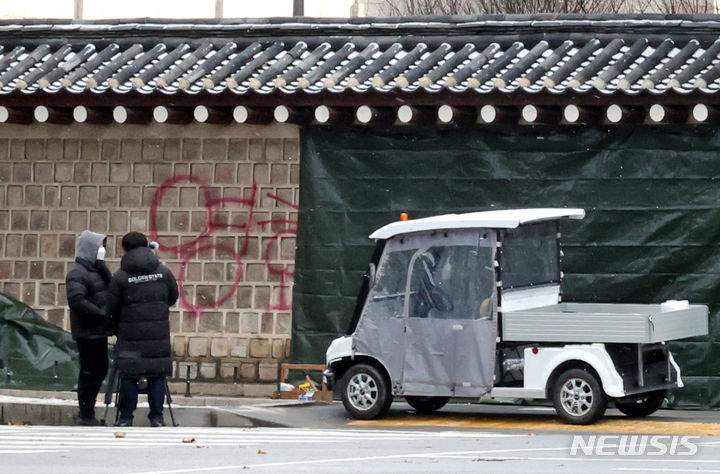 [서울=뉴시스] 김금보 기자 = 문화재청 궁능유적본부 직원들이 16일 오전 서울 종로구 국립고궁박물관 방향 경복궁 서편에서 스프레이 낙서로 훼손된 담벼락을 천으로 덮고 있다. 2023.12.16. kgb@newsis.com