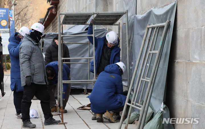 [서울=뉴시스] 김근수 기자 = 문화재청 궁능유적본부 직원들이 18일 서울 종로구 영추문 인근에서 스프레이 낙서로 훼손된 담벼락에 가람막을 설치하고 있다. 2023.12.18. ks@newsis.com