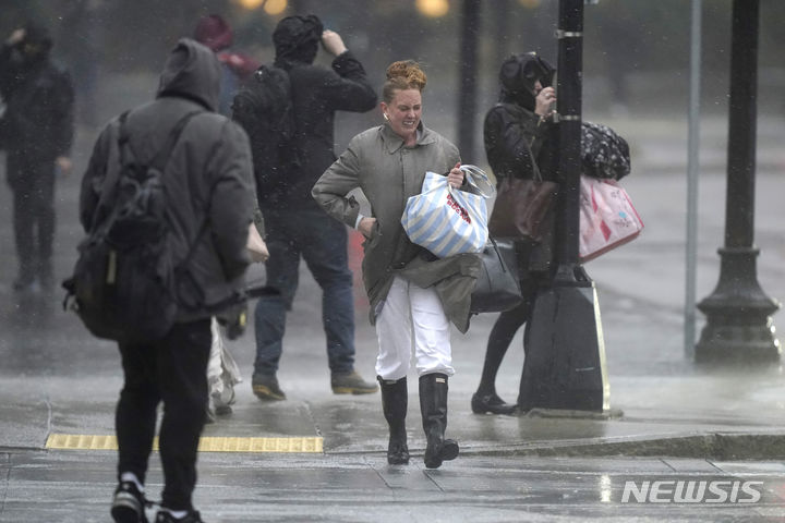 [보스턴=AP/뉴시스] 18일(현지시간) 미국 보스턴에서 시민들이 비바람을 맞으며 이동하고 있다. 2023.12.19.