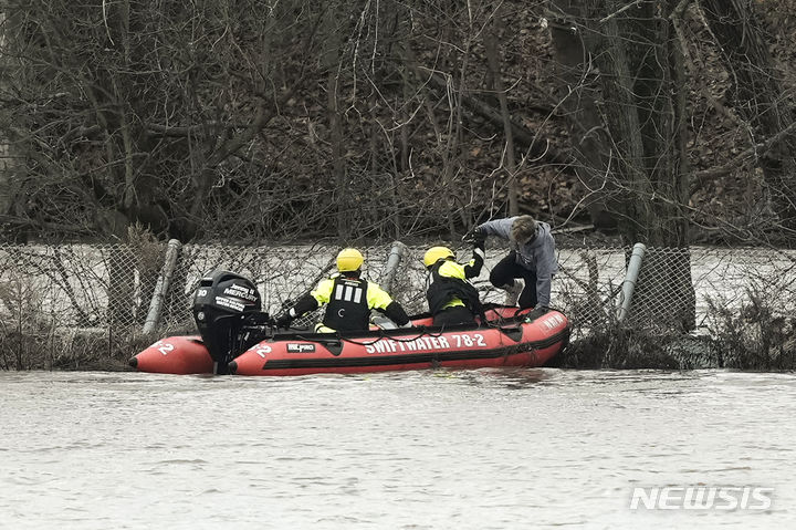 [펜실베니아=AP/뉴시스] 18일(현지시간) 미국 펜실베니아주 컬리지빌 퍼키오멘 크릭에서 구조대원들이 홍수 피해 현장에서 구조활동을 펼치고 있다. 2023.12.19.