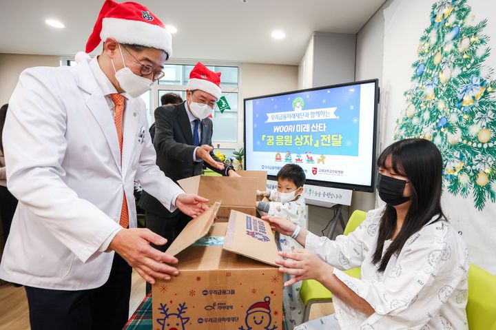 18일 서울 성북구 고려대 안암병원에서 (왼쪽부터)한승범 안암병원장, 장광익 우리금융지주 부사장이 환아들에게 선물을 전달하고 있다. (사진=우리금융 제공) *재판매 및 DB 금지