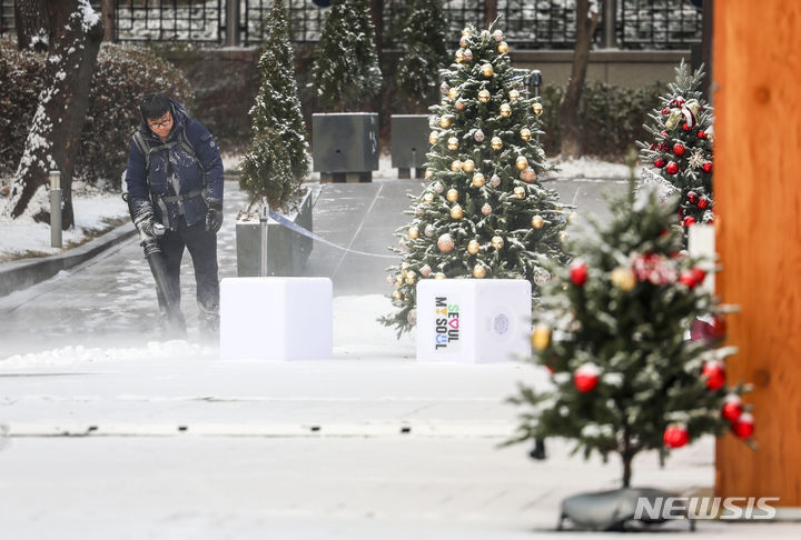 [서울=뉴시스] 정병혁 기자 = 크리스마스 이브인 24일 서울 종로구 광화문광장에서 관계자들이 밤에 내린 눈을 치우고 있다. 2023.12.24. jhope@newsis.com