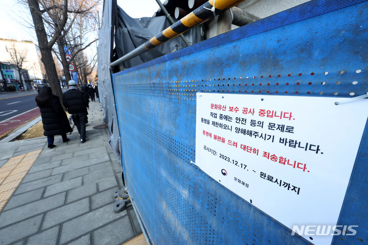 [서울=뉴시스] 김명년 기자 = 강추위로 중단됐던 경복궁 담장 낙서 작업이 재개된 26일 오후 서울 종로구 경복궁 서편 담장 보수 공사 현장에 안내문이 게시돼 있다. 2023.12.26. kmn@newsis.com