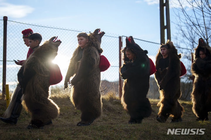 [라코바=AP/뉴시스] 26일(현지시간) 루마니아 북부 라코바 마을에서 곰 털 의상을 입은 어린이들이 마을 주민들을 위해 춤추기 전 행진하고 있다. 루마니아 '춤추는 곰 축제'는 동물 털을 입은 사람들이 집집이 다니며 노래하고 춤추면서 악을 물리치는 전통 풍습으로 기독교 이전 시대부터 유래한 것으로 알려졌다. 2023.12.27.