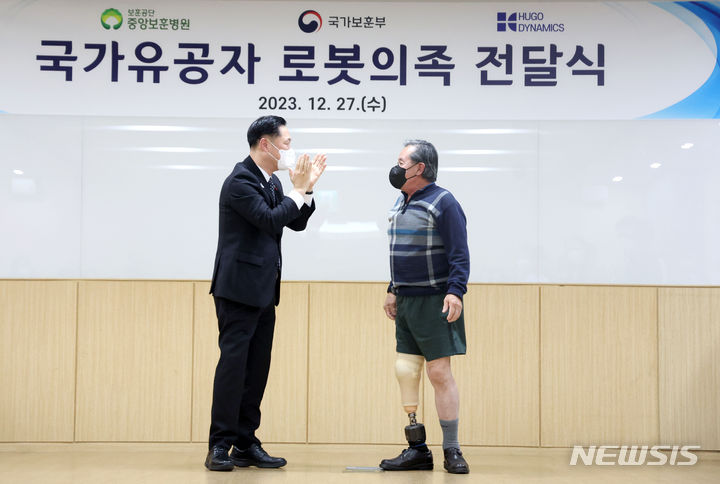 [서울=뉴시스] 김선웅 기자 = 이희완 국가보훈부 차관이 27일 서울 강동구 중앙보훈병원을 방문해 지뢰 사고로 다리를 잃은 장원종 국가유공자에게 로봇 의족을 전달한 후 기쁨을 나누고 있다. 2023.12.27. mangusta@newsis.com