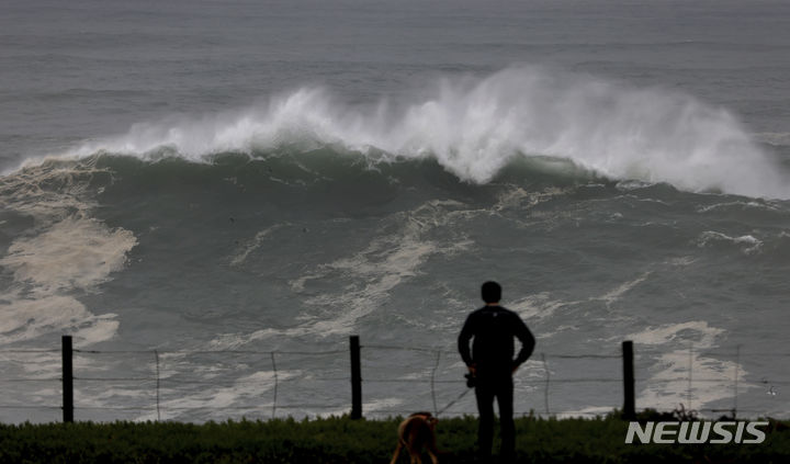 [캘리포니아=AP/뉴시스] 28일(현지시간) 미국 캘리포니아 카멧 던커스 랜딩 전망대에서 한 시민이 폭풍으로 인한 거대한 파도가 들이치는 모습을 바라보고 있다. 2023.12.29.