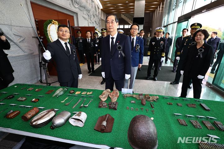 [서울=뉴시스] 사진공동취재단 = 한덕수(가운데) 국무총리가 29일 오전 서울 동작구 국립서울현충원 현충관에서 열린 6·25전사자 발굴유해 합동 봉안식에 앞서 6·25전사자 유품이 진열된 테이블 앞에서 이근원(왼쪽) 유해발굴감식단장의 설명을 듣고 있다. 2023.12.31. photo@newsis.com