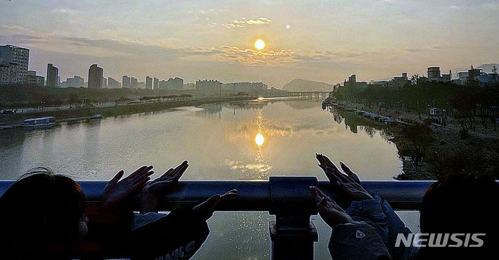 [대구 = 뉴시스] 정재익 기자 = 2024년 갑진년 (甲辰年) '청룡의 해' 새해를 맞이한 1일 오전 대구 동구 동촌유원지 해맞이다리에서 학생들이 일출에 포즈를 취하고 있다. 2024.01.01. jjikk@newsis.com