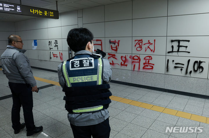[서울=뉴시스] 고범준 기자 = 2일 오전 서울 영등포구 9호선 국회의사당역 6번출구 벽에 스프레이 낙서가 그려져 있다. 경찰이 현장을 확인하고 있다. 2024.01.02. bjko@newsis.com