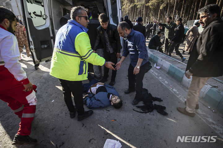 [케르만(이란)=AP/뉴시스]3일(현지시간) 이란 혁명수비대(IRGC) 정예부대 쿠드스군 사령관 가셈 솔레이마니의 추모식에서 2차례 폭발이 발생해 최소 103명이 사망했다고 이란 국영 IRNA 통신이 보도했다. 사진은 이날 폭발이 발생한 뒤 부상자 옆에 사람들이 몰려있는 모습. 2024.01.04.