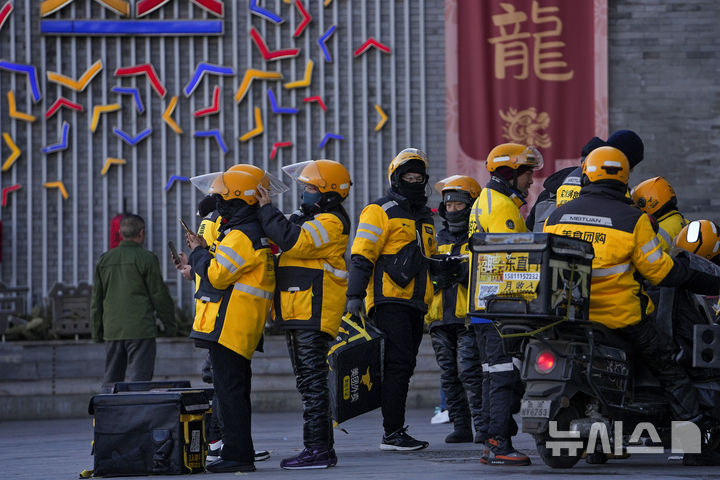 [베이징=AP/뉴시스] 11월 중국 소비자물가지수(CPI)가 전년 동월 대비 0.7% 상승했다고 10일 중국 국가통계국이 발표했다. 사진은 지난해 1월 5일 중국 베이징에서 배달플랫폼 메이퇀의 배달원들이 거리에 모여 있는 모습. 2025.12.10