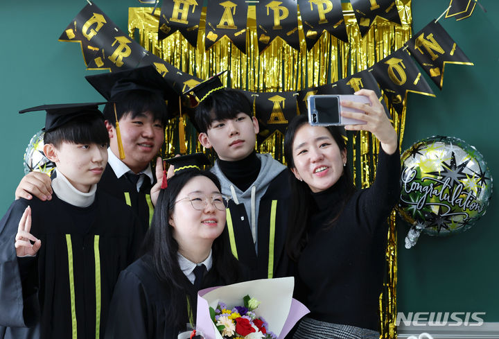 [서울=뉴시스] 홍효식 기자 = 5일 서울 성동구 덕수고등학교 행당분교에서 열린 졸업식에서 졸업생들과 선생님이 기념촬영하고 있다. 덕수고 행당분교(특성화계열)는 올해 폐교되고, 일반계열은 지난해 송파구 위례신도시로 이전했다. 2024.01.05. yesphoto@newsis.com