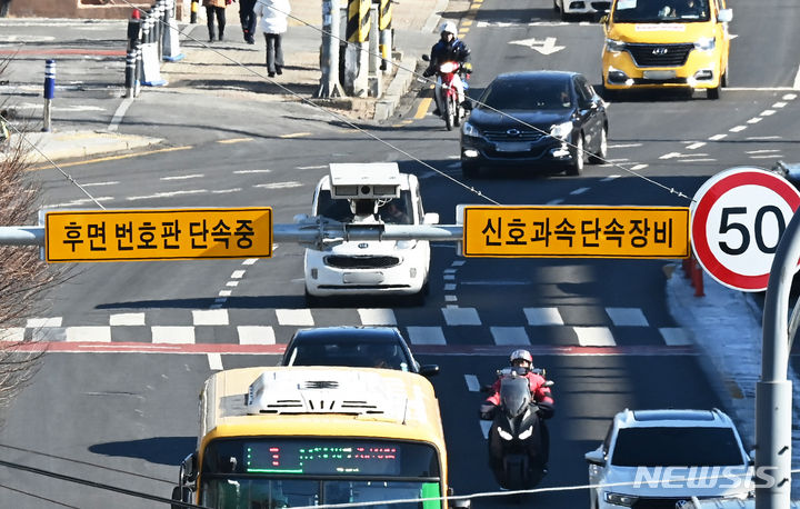 [수원=뉴시스] 김종택 기자 = 8일 경기도 수원시 한 도로에 설치된 후면 무인교통 단속 카메라 앞을 오토바이 운전자가 지나가고 있다. 경찰청은 오늘부터 뒷번호판을 찍는 후면 단속카메라를 활용해 이륜차 신호·과속 단속과 안전모 미착용을 무인 단속한다고 밝혔다. 2024.01.08. jtk@newsis.com