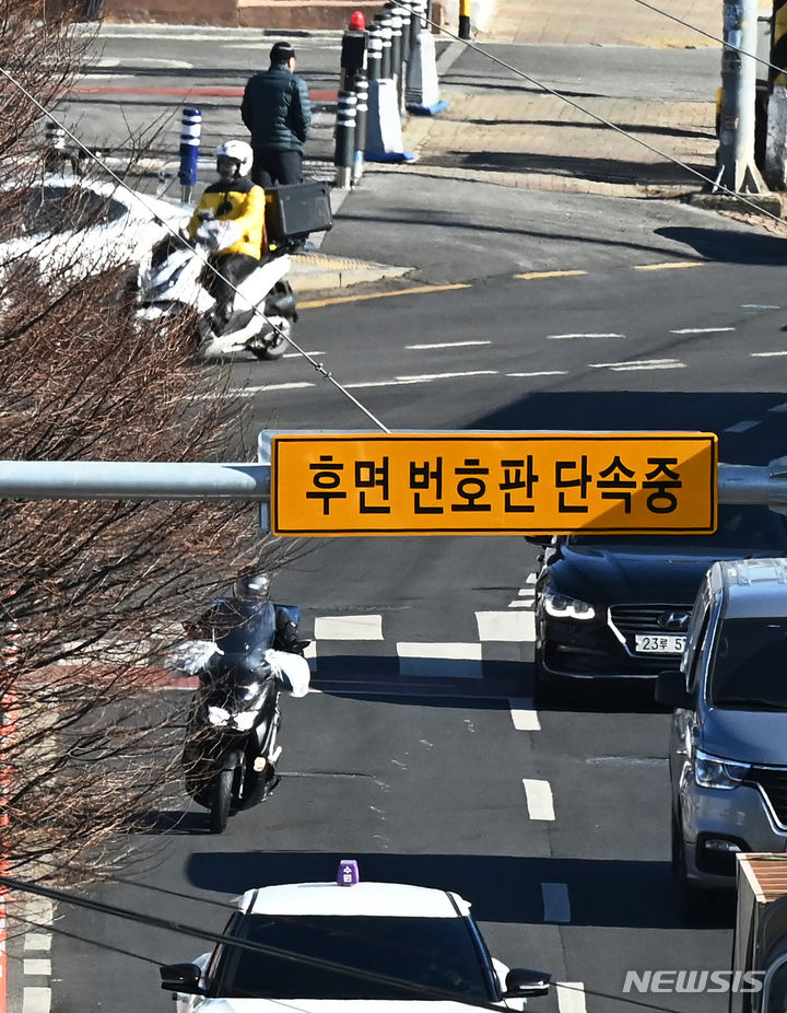 [수원=뉴시스] 김종택 기자 = 8일 경기도 수원시 한 도로에 설치된 후면 무인교통 단속 카메라 앞을 오토바이 운전자가 지나가고 있다. 경찰청은 오늘부터 뒷번호판을 찍는 후면 단속카메라를 활용해 이륜차 신호·과속 단속과 안전모 미착용을 무인 단속한다고 밝혔다. 2024.01.08. jtk@newsis.com