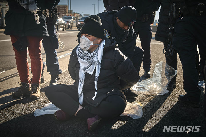 [뉴욕=AP/뉴시스] 경찰이 8일(현지시간) 미국 뉴욕 브루클린 다리에서 이스라엘-팔레스타인 전쟁 휴전을 촉구하는 시위대를 체포하고 있다. 2024.01.09.