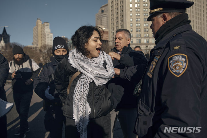 [뉴욕=AP/뉴시스] 경찰이 8일(현지시간) 미국 뉴욕 브루클린 다리에서 이스라엘-팔레스타인 전쟁 휴전을 촉구하는 시위대를 체포하고 있다. 2024.01.09.