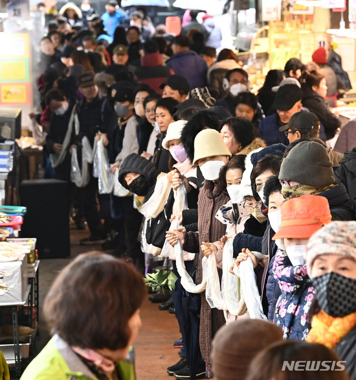 [수원=뉴시스] 김종택 기자 = 17일 경기도 수원시 팔달구 못골시장에서 열린 '못골시장과 함께하는 가래떡 나눔 행사'에 참석한 시장상인과 시민들이 180m 길이의 가래떡을 이어 잡는 퍼포먼스를 하고 있다. 새해를 맞아 무병장수를 기원하며 긴 가래떡을 뽑는 가래떡 나눔은 못골시장의 대표 행사다. 2024.01.17. jtk@newsis.com