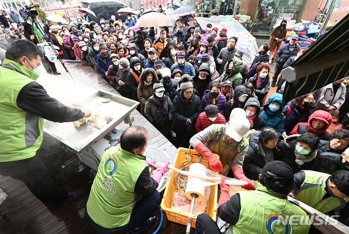 [수원=뉴시스] 김종택 기자 = 17일 경기도 수원시 팔달구 못골시장에서 열린 '못골시장과 함께하는 가래떡 나눔 행사'에 참석한 시장상인과 시민들이 180m 길이의 가래떡을 전달받기 위해 길게 줄 서 있다. 새해를 맞아 무병장수를 기원하며 긴 가래떡을 뽑는 가래떡 나눔은 못골시장의 대표 행사다. 2024.01.17. jtk@newsis.com