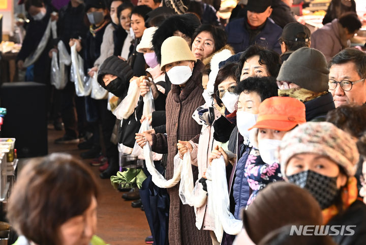 [수원=뉴시스] 김종택 기자 = 17일 경기도 수원시 팔달구 못골시장에서 열린 '못골시장과 함께하는 가래떡 나눔 행사'에 참석한 시장상인과 시민들이 180m 길이의 가래떡을 이어 잡는 퍼포먼스를 하고 있다. 새해를 맞아 무병장수를 기원하며 긴 가래떡을 뽑는 가래떡 나눔은 못골시장의 대표 행사다. 2024.01.17. jtk@newsis.com