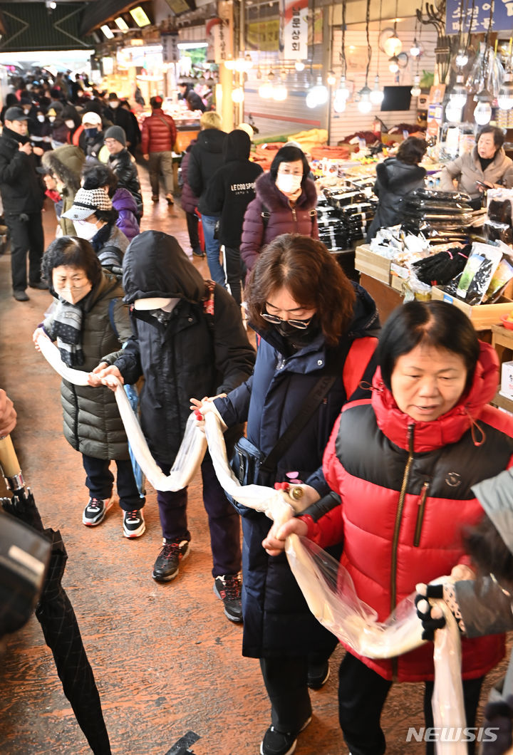 [수원=뉴시스] 김종택 기자 = 17일 경기도 수원시 팔달구 못골시장에서 열린 '못골시장과 함께하는 가래떡 나눔 행사'에 참석한 시장상인과 시민들이 180m 길이의 가래떡을 이어 잡는 퍼포먼스를 하고 있다. 새해를 맞아 무병장수를 기원하며 긴 가래떡을 뽑는 가래떡 나눔은 못골시장의 대표 행사다. 2024.01.17. jtk@newsis.com