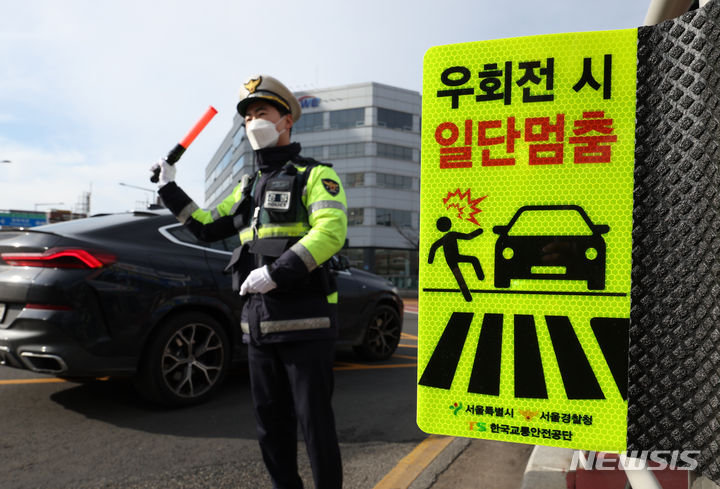 [서울=뉴시스] 고승민 기자 = 교차로 우회전 일시정지 도로교통법 개정 및 시행 1주년을 사흘 앞둔 19일 서울의 한 사거리에서 경찰이 우회전 차량을 대상으로 계도 활동을 하고 있다. 2024.01.19. kkssmm99@newsis.com