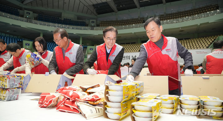 [창원=뉴시스] 20일 경남 창원시 마산회원구 마산실내체육관에서 윤한홍(오른쪽부터) 국회의원, 예경탁 BNK경남은행장 등이 생필품·식료품 꾸러미 포장 작업을 하고 있다.(사진=BNK경남은행 제공)2024.01.20.  photo@newsis.com