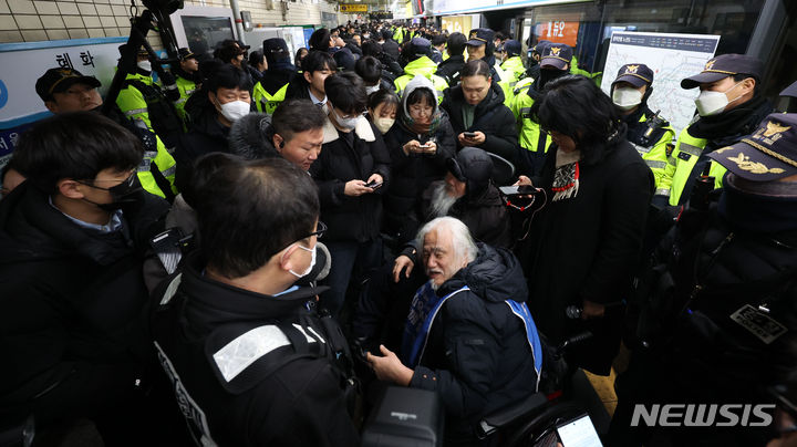 [서울=뉴시스] 김선웅 기자 = 전국장애인차별철폐연대 박경석 대표와 회원들이 22일 서울 지하철 4호선 혜화역에서 장애인 이동권 보장을 촉구하는 중 교통공사 관계자로부터 퇴거 요구를 받고 있다. 2024.01.22. mangusta@newsis.com