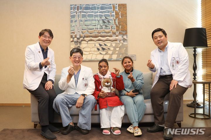 [서울=뉴시스] 마다가스카르 거대신경섬유종 환자 바우술루의 수술성공 및 퇴원축하를 기념해 참석자들이 기념촬영을 하고 있다. 왼쪽부터 안암병원 내분비내과 김신곤 교수, 한승범 안암병원장, 바우술루, 환자 보호자 겸 통역 라자피마노로, 안암병원 성형외과 정재호 교수. (사진= 고려대 안암병원 제공) 2024.01.24. photo@newsis.com. 