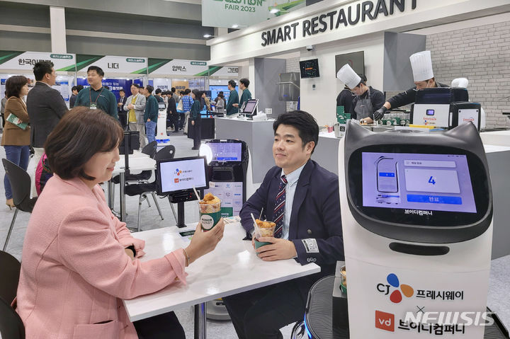 [서울=뉴시스] CJ프레시웨이가 지난해 10월 개최된 '푸드 솔루션 페어 2023'에서 관람객들이 '스마트레스토랑' 코너에서 제공하는 로봇 조리 메뉴를 시식하고 있다. (사진=CJ프레시웨이 제공)&nbsp; 