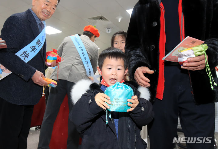 [제주=뉴시스] 우장호 기자 = 민족 최대 명절인 설 연휴를 앞둔 8일 오후 제주국제공항 1층 국제선 도착장에서 제주~상하이 직항노선을 타고 온 한 중국인 어린이가 기념품으로 받은 복주머니를 신기한 듯 바라보고 있다. 2024.02.08. woo1223@newsis.com