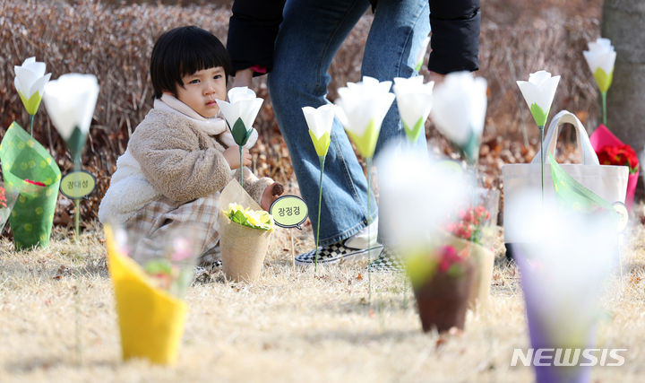 [대구=뉴시스] 이무열 기자 = 18일 대구 동구 시민안전테마파크에서 열린 2·18 대구지하철 화재 참사 21주기 추모식을 찾은 어린이가 추모 꽃을 바라보고 있다. 2024.02.18. lmy@newsis.com