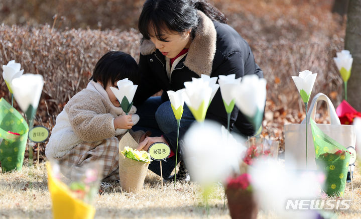 [대구=뉴시스] 이무열 기자 = 18일 대구 동구 시민안전테마파크에서 열린 2·18 대구지하철 화재 참사 21주기 추모식을 찾은 어린이가 추모 꽃밭에 꽃을 꽂고 있다. 2024.02.18. lmy@newsis.com