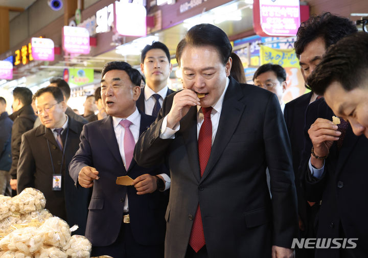 [울산=뉴시스] 조수정 기자 = 윤석열 대통령이 21일 울산 남구 신정상가시장을 방문해 전통과자를 맛보고 있다. 2024.02.21. chocrystal@newsis.com