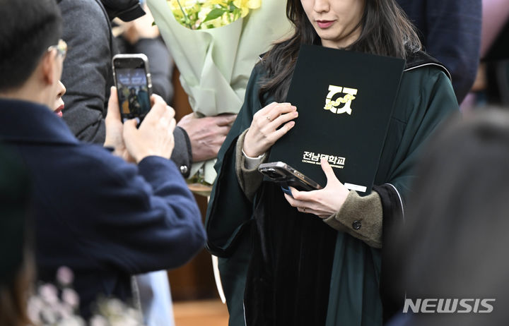 [광주=뉴시스] 박기웅 기자 = 23일 오전 광주 동구 전남대학교 학동캠퍼스 의과대학 명학회관 대강당에서 '2023학년도 의과대학 제72회 히포크라테스 선서식'이 열렸다. 졸업생들이 친구, 가족들과 기념촬영을 하고 있다. 2024.02.23. pboxer@newsis.com