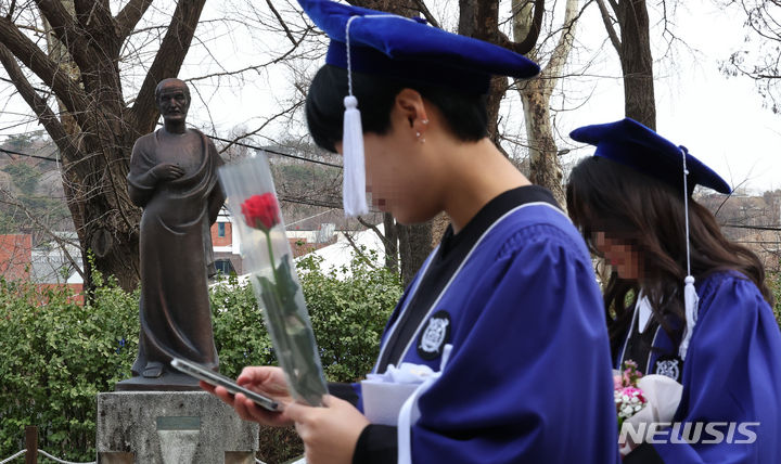 [서울=뉴시스] 최진석 기자 = 27일 서울 종로구 서울대학교 의과대학 행정관에서 열린 서울대 의대 2023학년도 전기 의과대학·대학원 학위수여식 참석하는 졸업생들이 히포크라테스 동상 앞을 지나고 있다. 2024.02.27. myjs@newsis.com