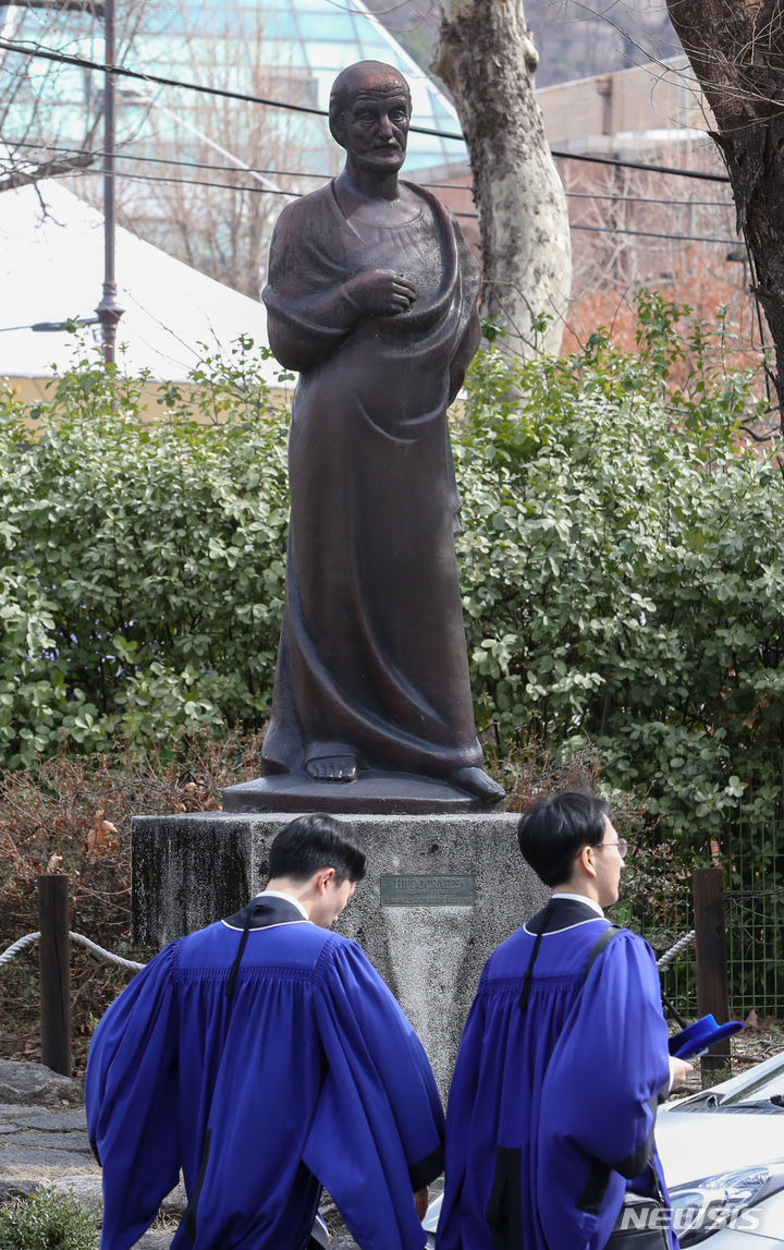 [서울=뉴시스] 이동현 인턴기자 = 27일 서울 종로구 서울대학교 연건캠퍼스에서 의과대학·대학원 학위수여식이 열린 가운데 졸업생들이 히포크라테스상 앞을 지나가고 있다. 2024.02.27. koiflag@newsis.com